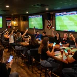 Fans engaging in kèo nhà cái hôm nay while cheering for their teams at a lively sports bar event